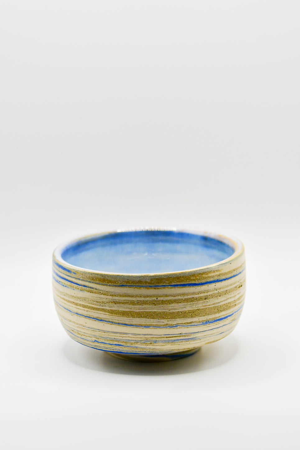 Ceramic bowl with blue and beige stripes on a white background