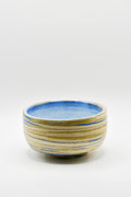 Ceramic bowl with blue and beige stripes on a white background
