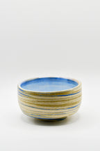 Ceramic bowl with blue and beige stripes on a white background