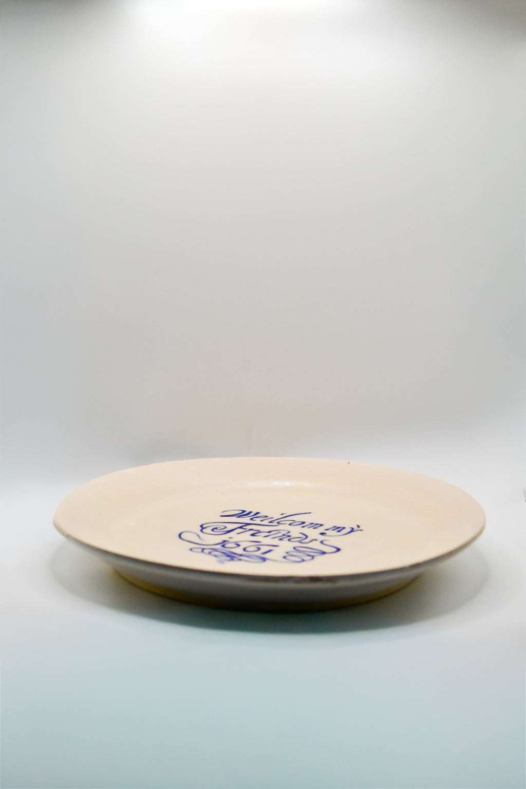 Round white plate with blue text 'Welcom my Friends 1661' on a white background