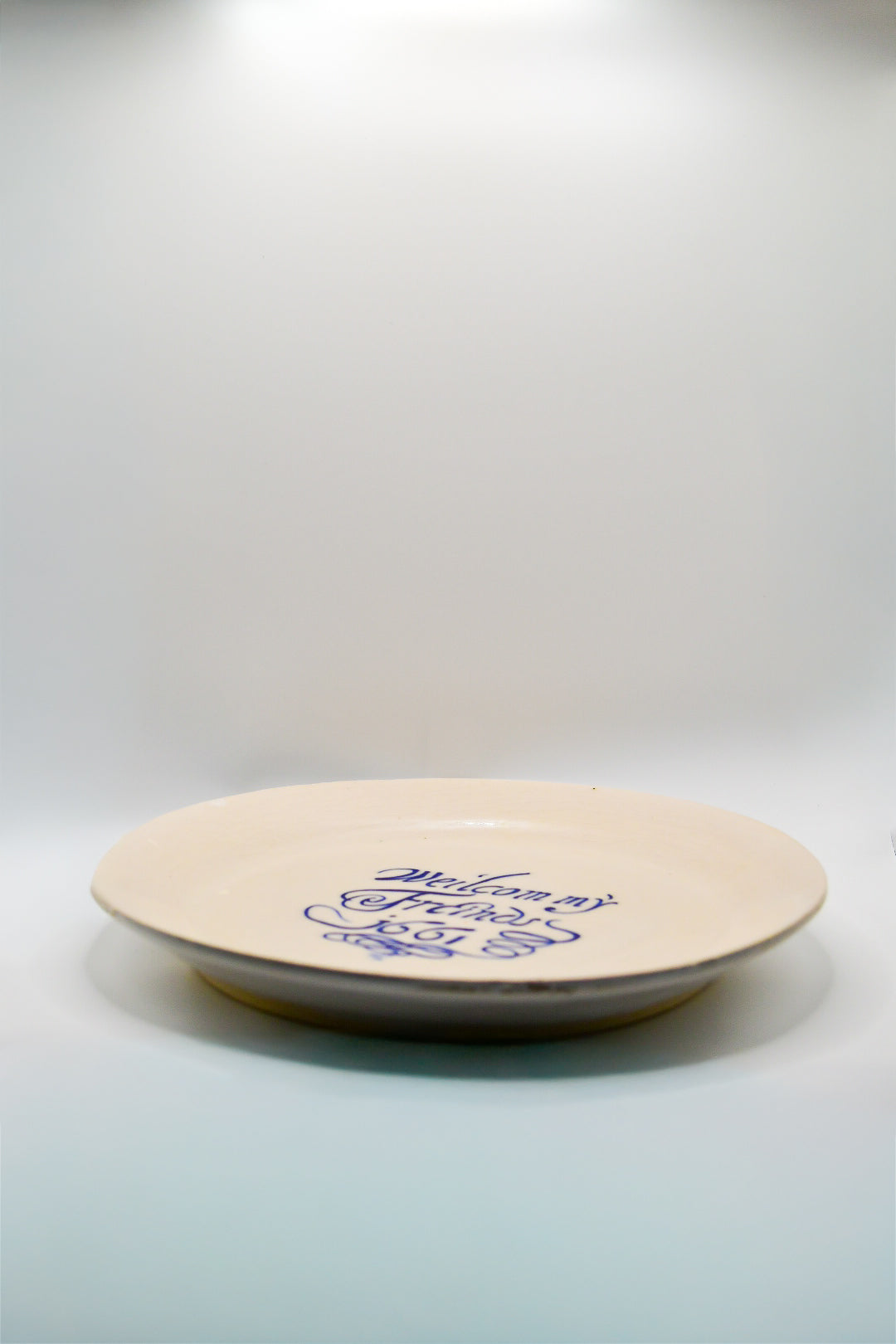 Round white plate with blue text 'Welcom my Friends 1661' on a white background
