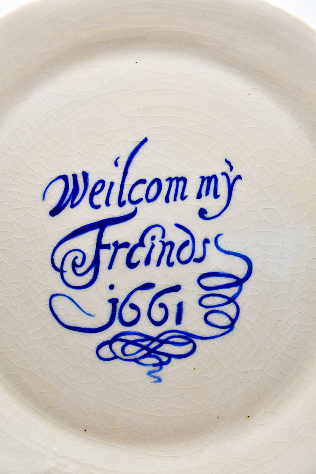 Round white plate with blue text 'Welcom my Friends 1661' on a white background