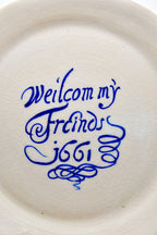 Round white plate with blue text 'Welcom my Friends 1661' on a white background