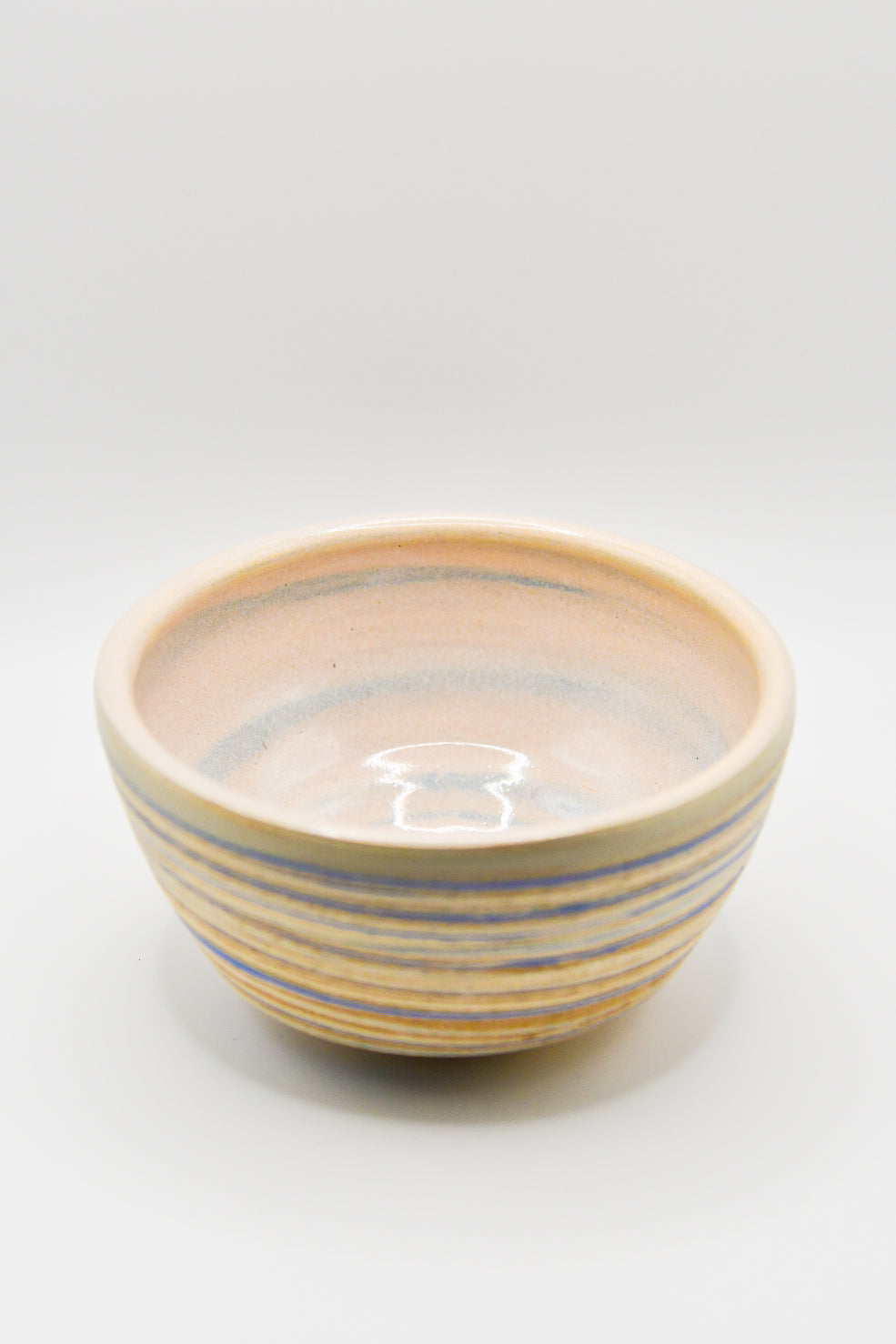 Ceramic bowl with blue and beige stripes on a white background