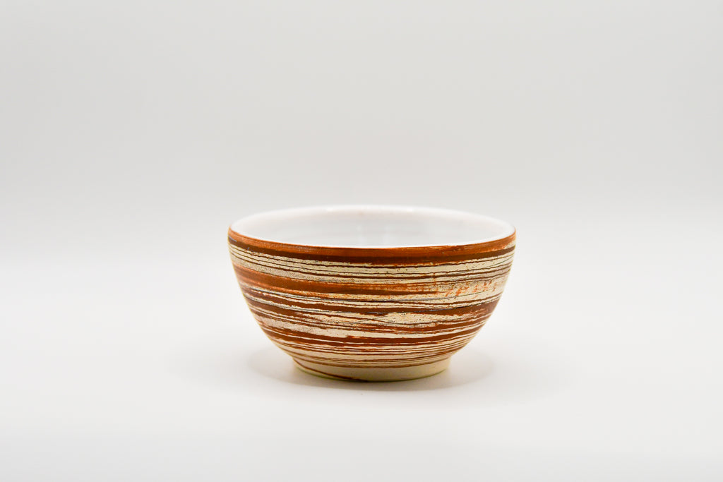 Ceramic bowl with brown and beige stripes on a white background