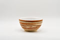 Ceramic bowl with brown and beige stripes on a white background