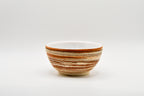 Ceramic bowl with brown and beige stripes on a white background