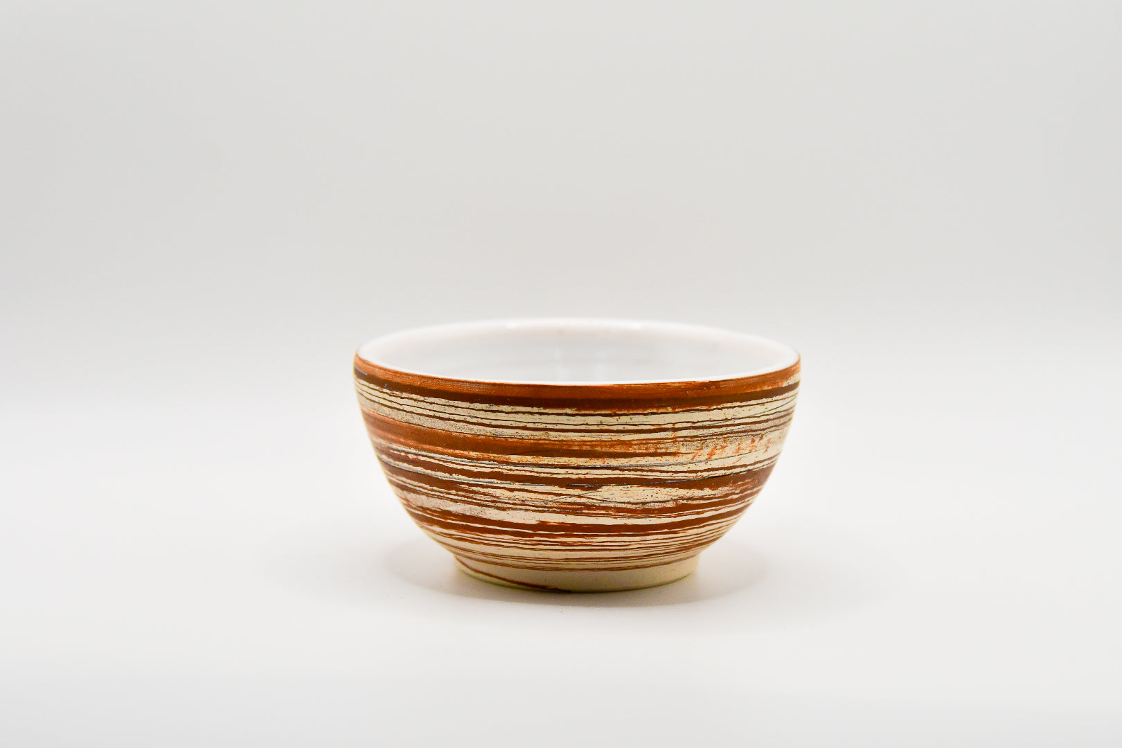 Ceramic bowl with brown and beige stripes on a white background