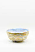 Ceramic bowl with blue and gold stripes on a white background