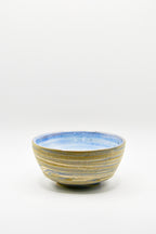 Ceramic bowl with blue and gold stripes on a white background