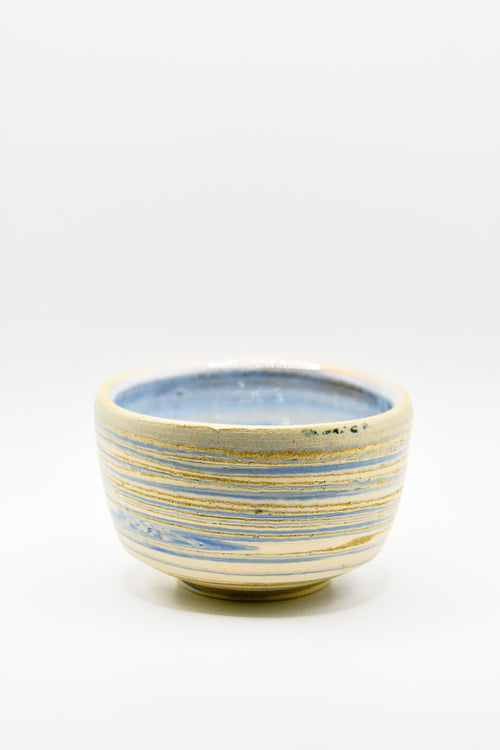 Ceramic bowl with blue and gold stripes on a white background