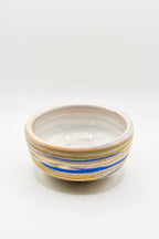 Ceramic bowl with blue and gold stripes on a white background