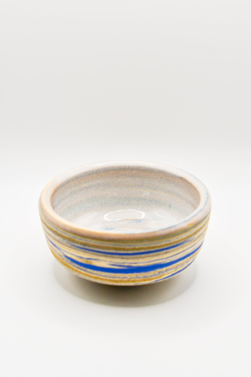 Ceramic bowl with blue and gold stripes on a white background