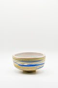Ceramic bowl with blue and gold stripes on a white background