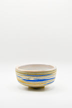 Ceramic bowl with blue and gold stripes on a white background