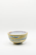 Ceramic bowl with blue and yellow stripes on a white background