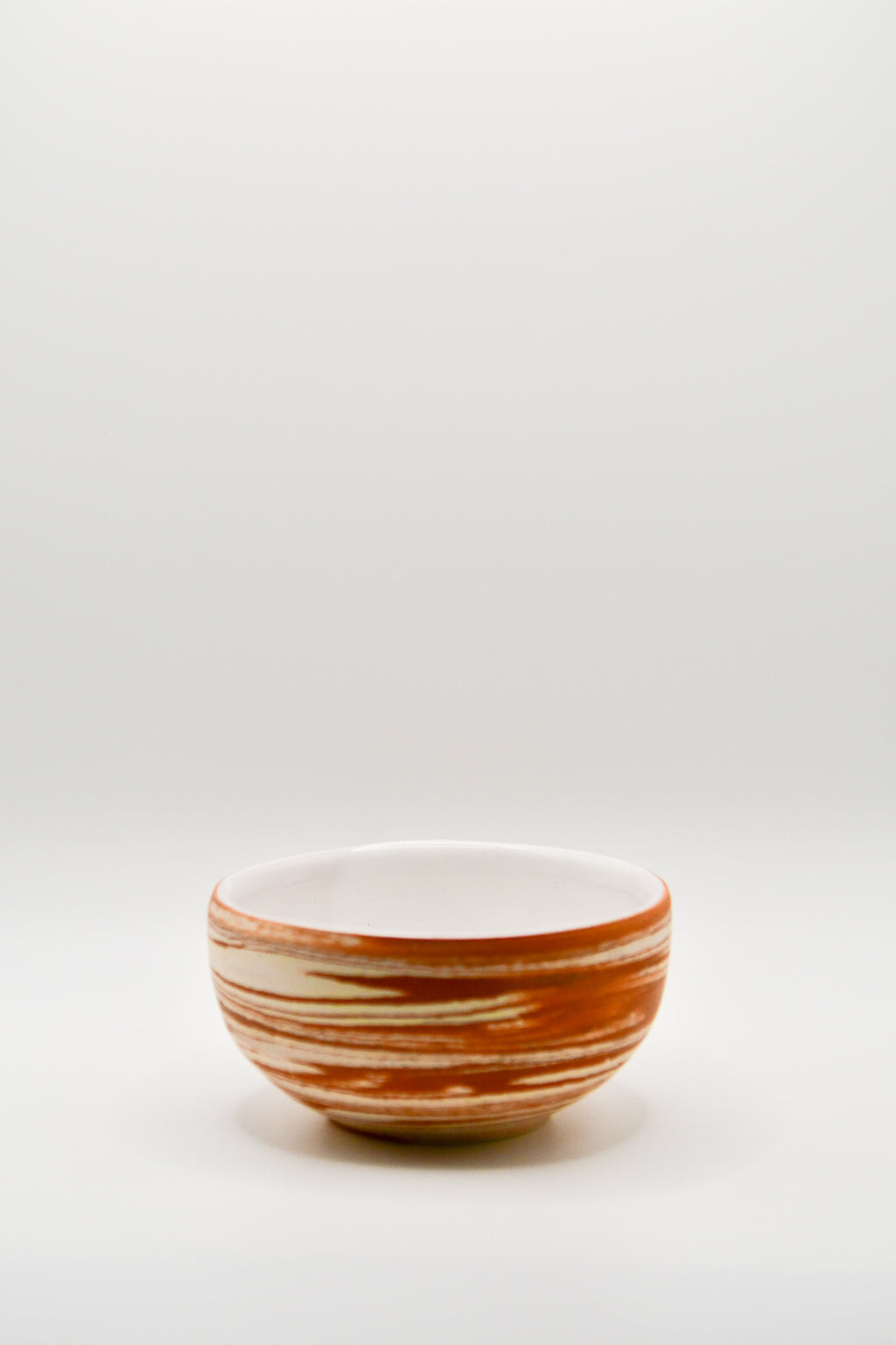 Small ceramic bowl with brown and white stripes on a light gray background