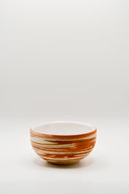 Small ceramic bowl with brown and white stripes on a light gray background