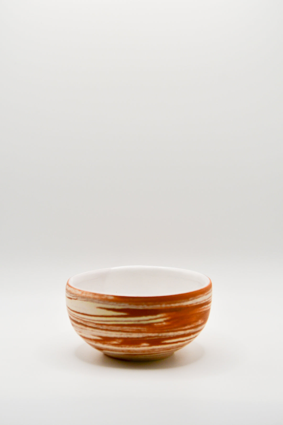 Small ceramic bowl with brown and white stripes on a light gray background