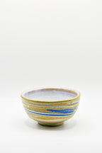 Ceramic bowl with blue and yellow stripes on a white background