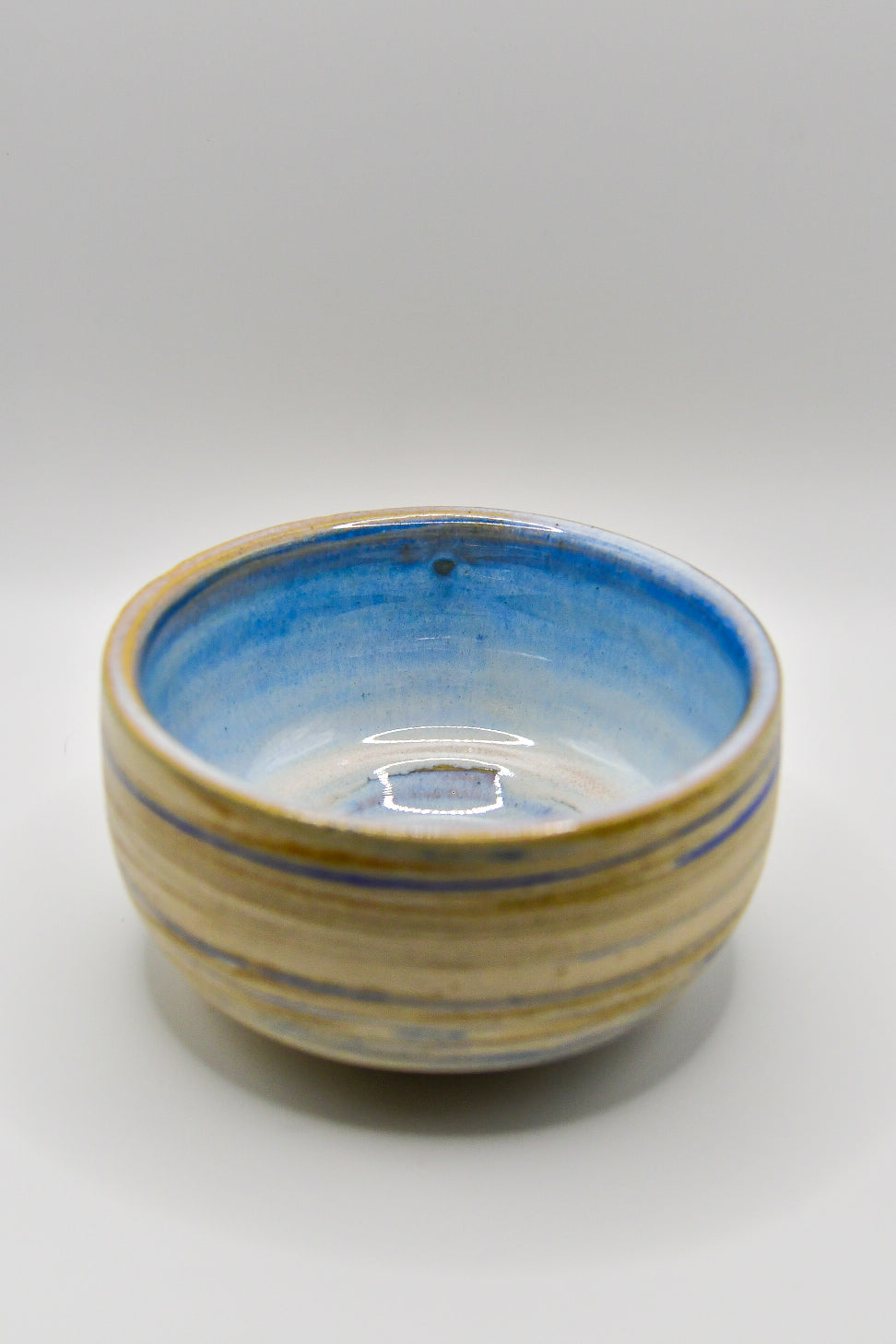 Ceramic bowl with blue and beige stripes on a white background