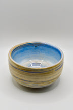 Ceramic bowl with blue and beige stripes on a white background