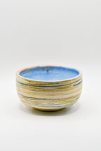 Ceramic bowl with blue and beige stripes on a white background