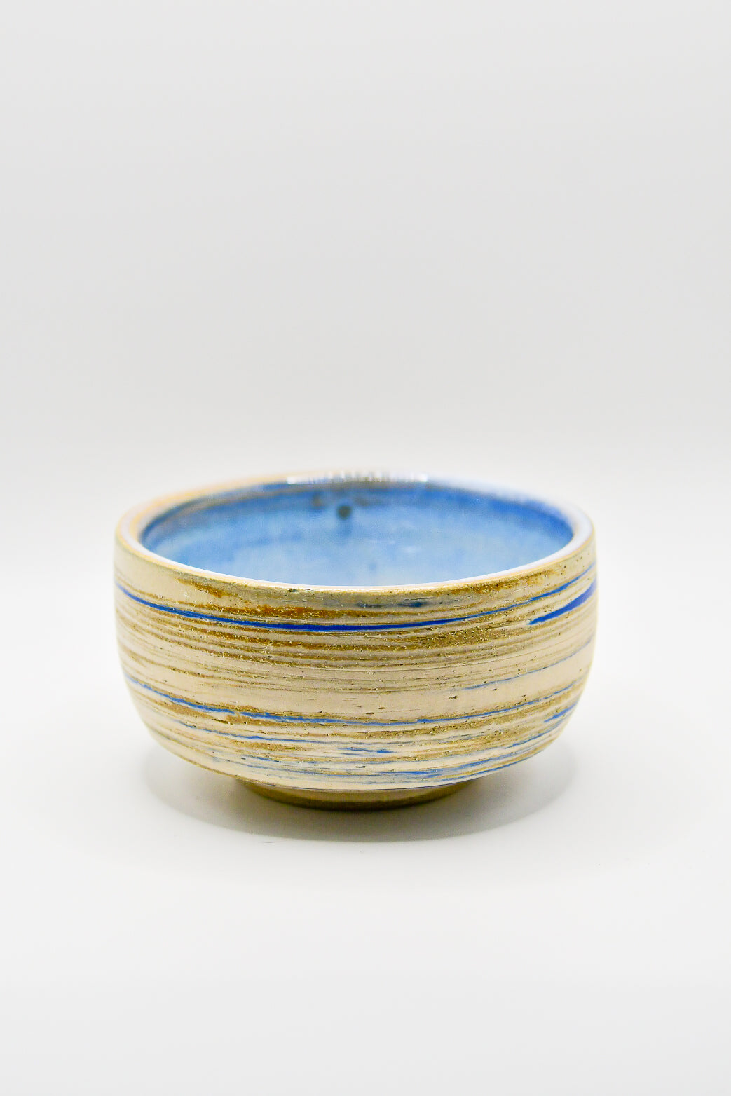 Ceramic bowl with blue and beige stripes on a white background