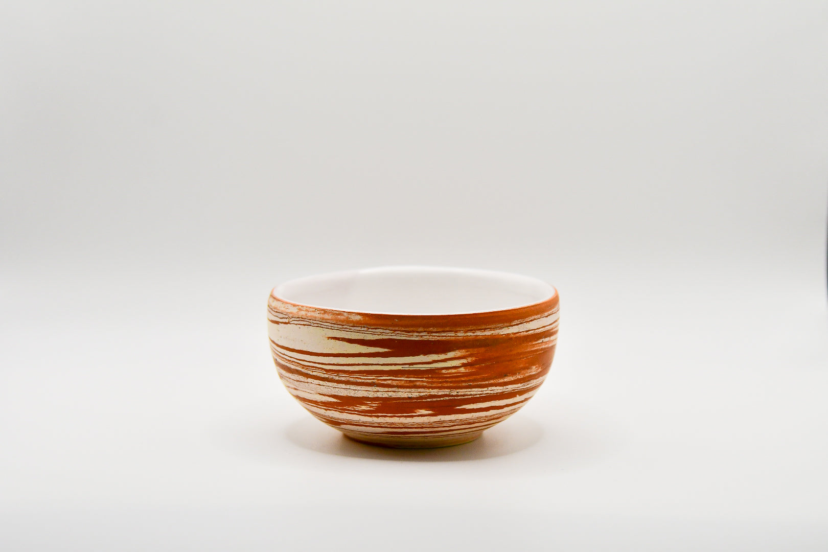 Ceramic bowl with brown and white stripes on a white background