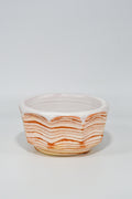 Ceramic bowl with wavy orange pattern on a white background