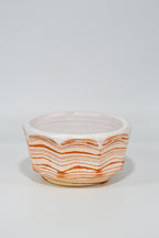 Ceramic bowl with wavy orange pattern on a white background