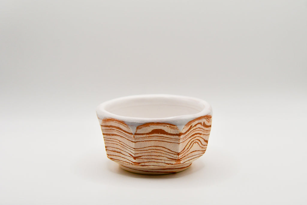 Small ceramic bowl with wavy brown pattern on a white background