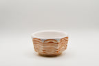 Small ceramic bowl with wavy brown pattern on a white background
