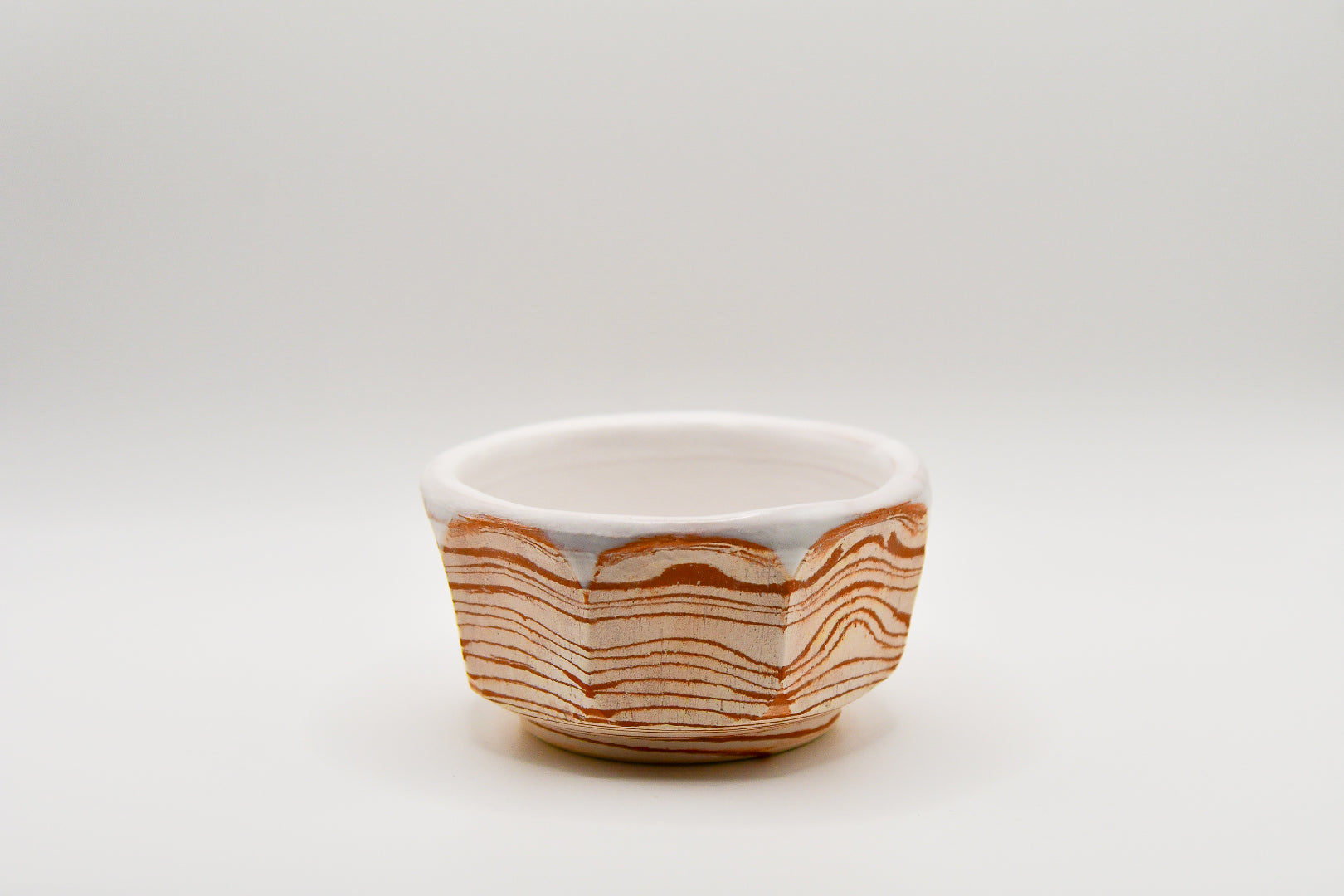 Small ceramic bowl with wavy brown pattern on a white background