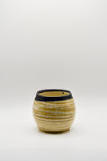 Small ceramic cup with ribbed texture and black rim on a white background