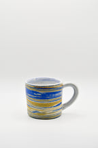 Ceramic mug with blue and gold stripes on a white background