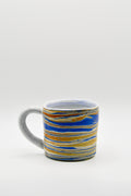 Ceramic mug with blue and orange striped pattern on a white background