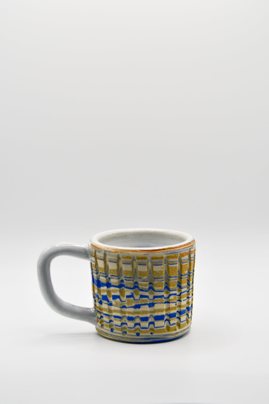 Ceramic mug with blue and beige pattern on a white background