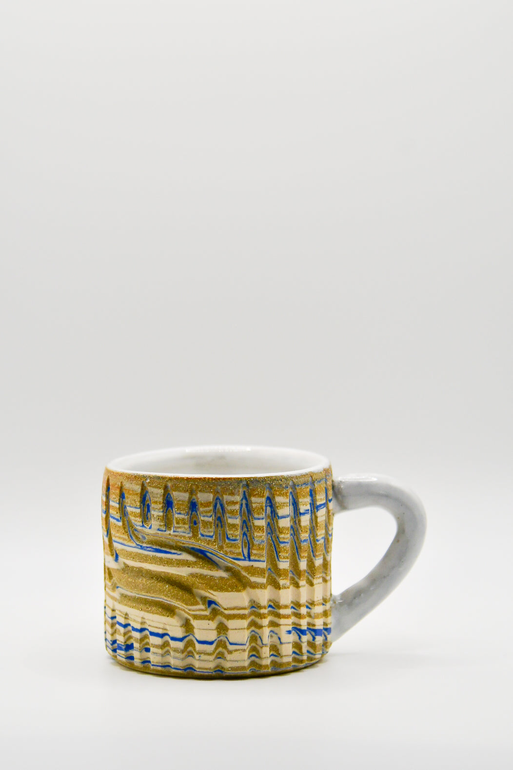Ceramic mug with blue and beige pattern on a white background