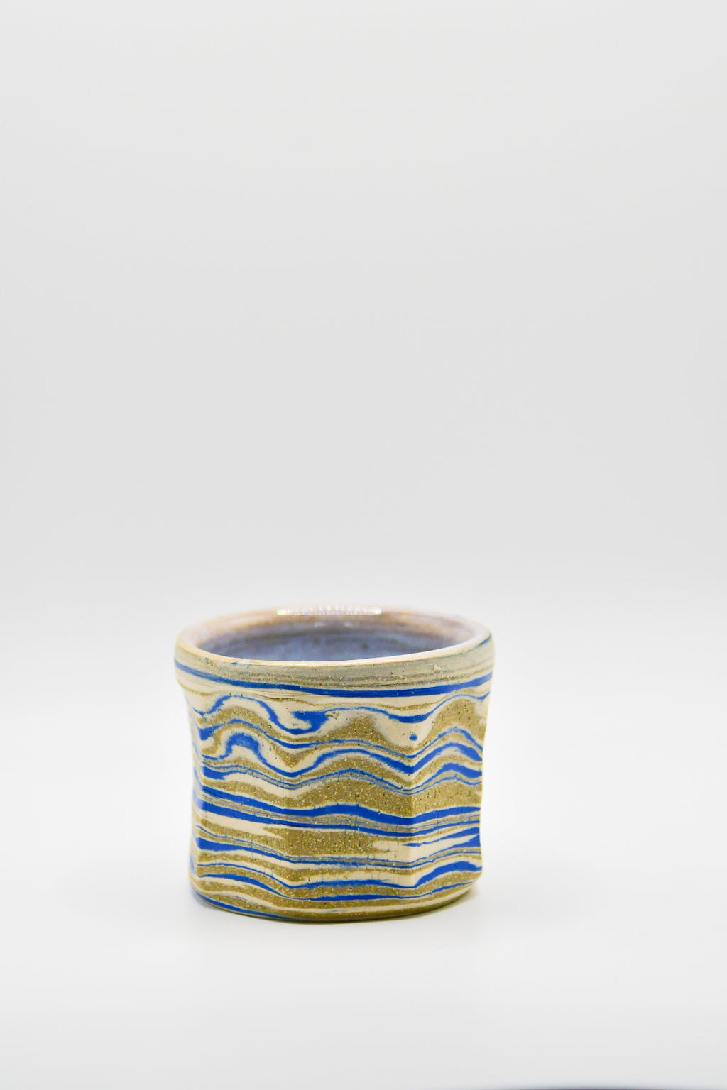 Ceramic cup with blue and beige pattern on a white background