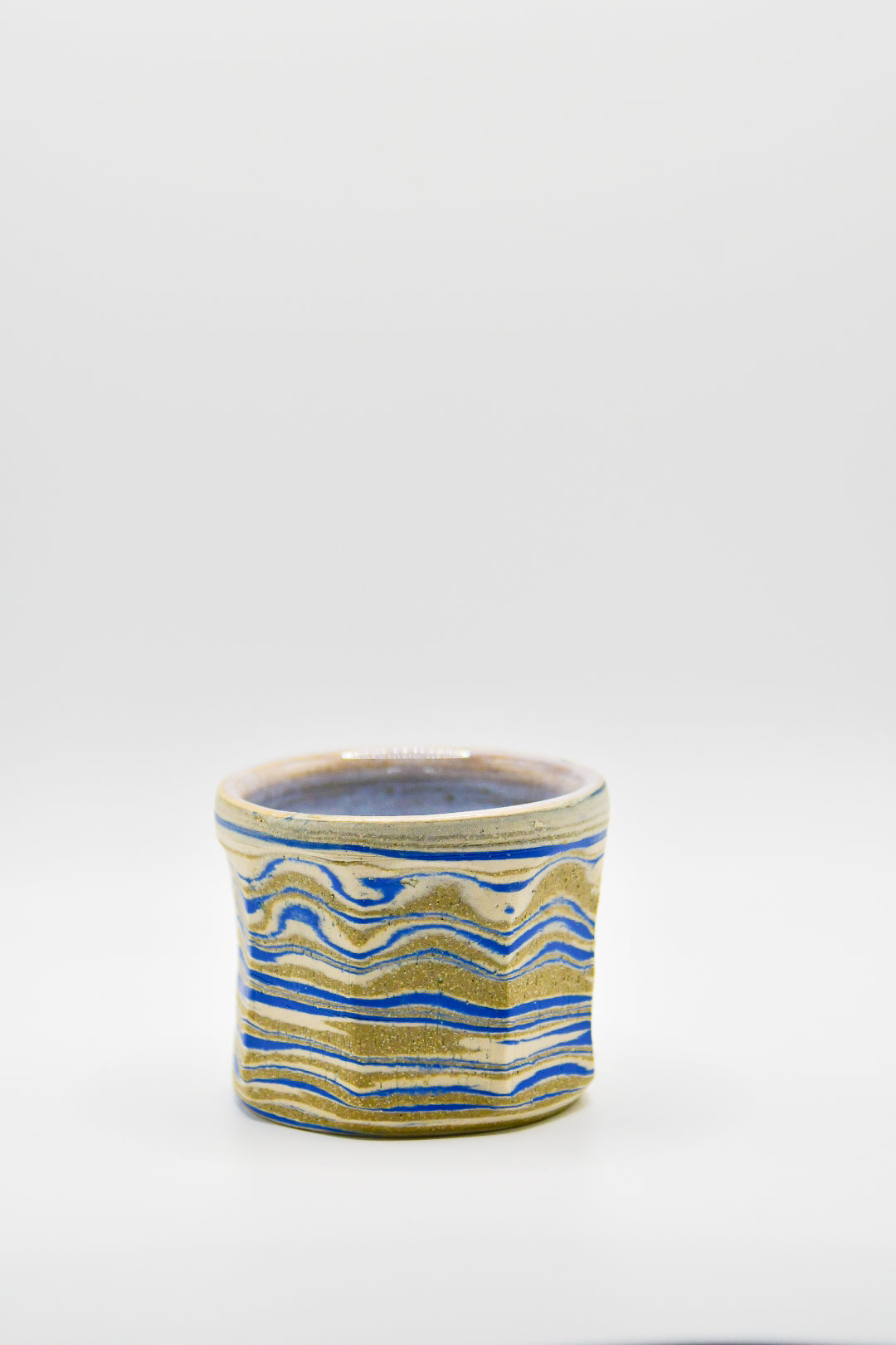 Ceramic cup with blue and beige pattern on a white background
