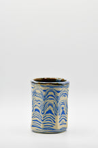 Ceramic cup with blue and beige pattern on a white background