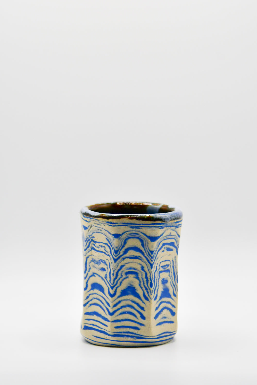 Ceramic cup with blue and beige pattern on a white background