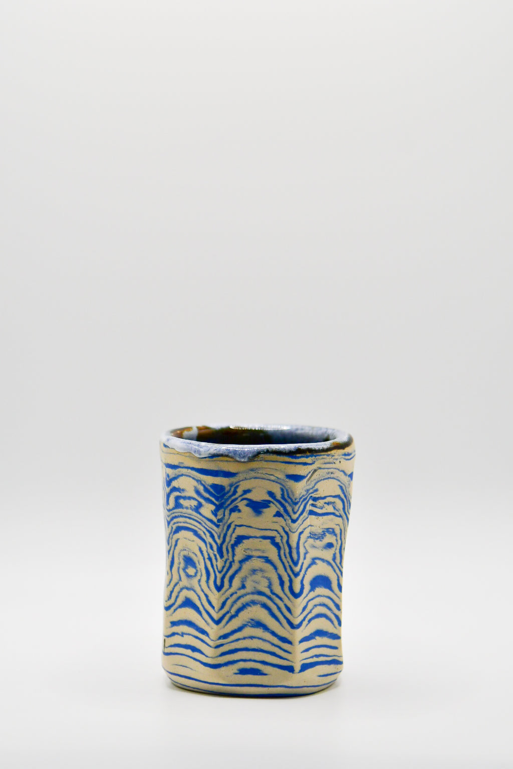 Ceramic cup with blue and beige pattern on a white background