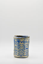 Ceramic cup with blue and beige pattern on a white background