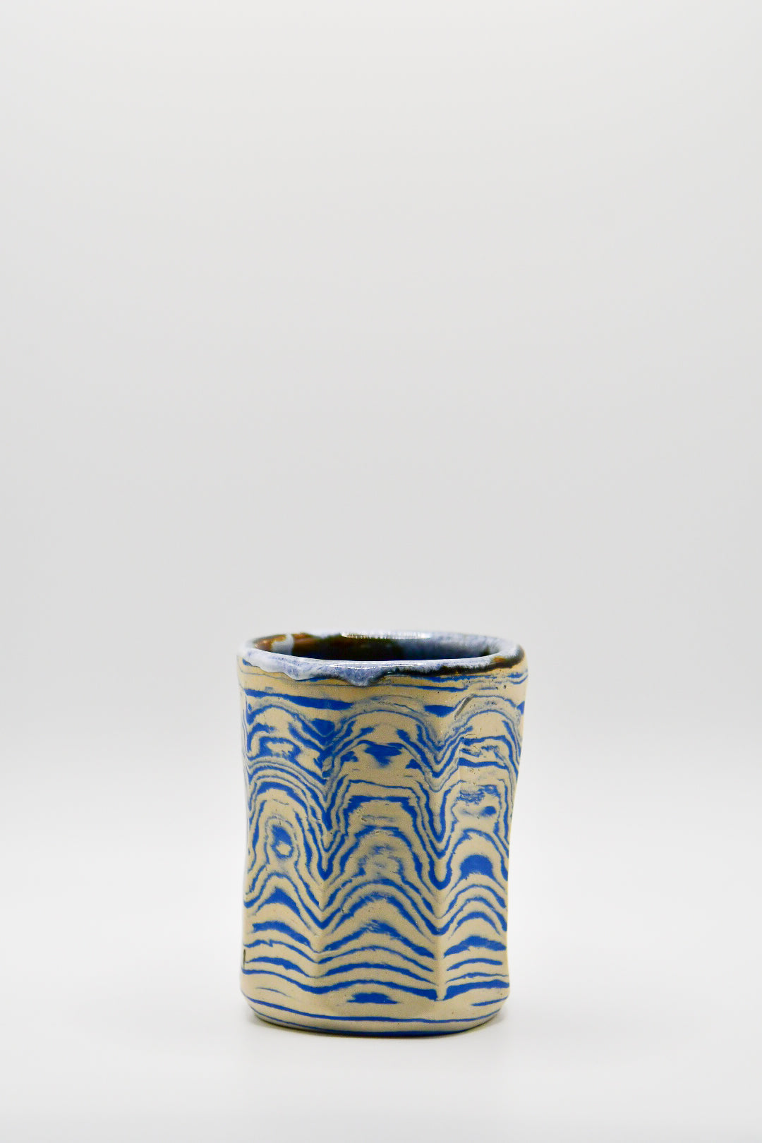 Ceramic cup with blue and beige pattern on a white background