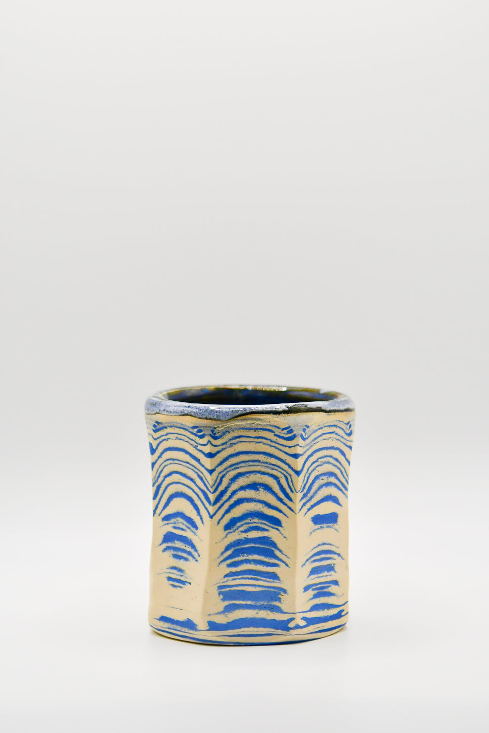 Ceramic cup with blue and beige pattern on a white background