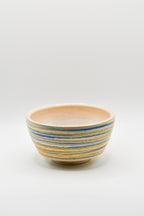 Ceramic bowl with blue and beige stripes on a white background