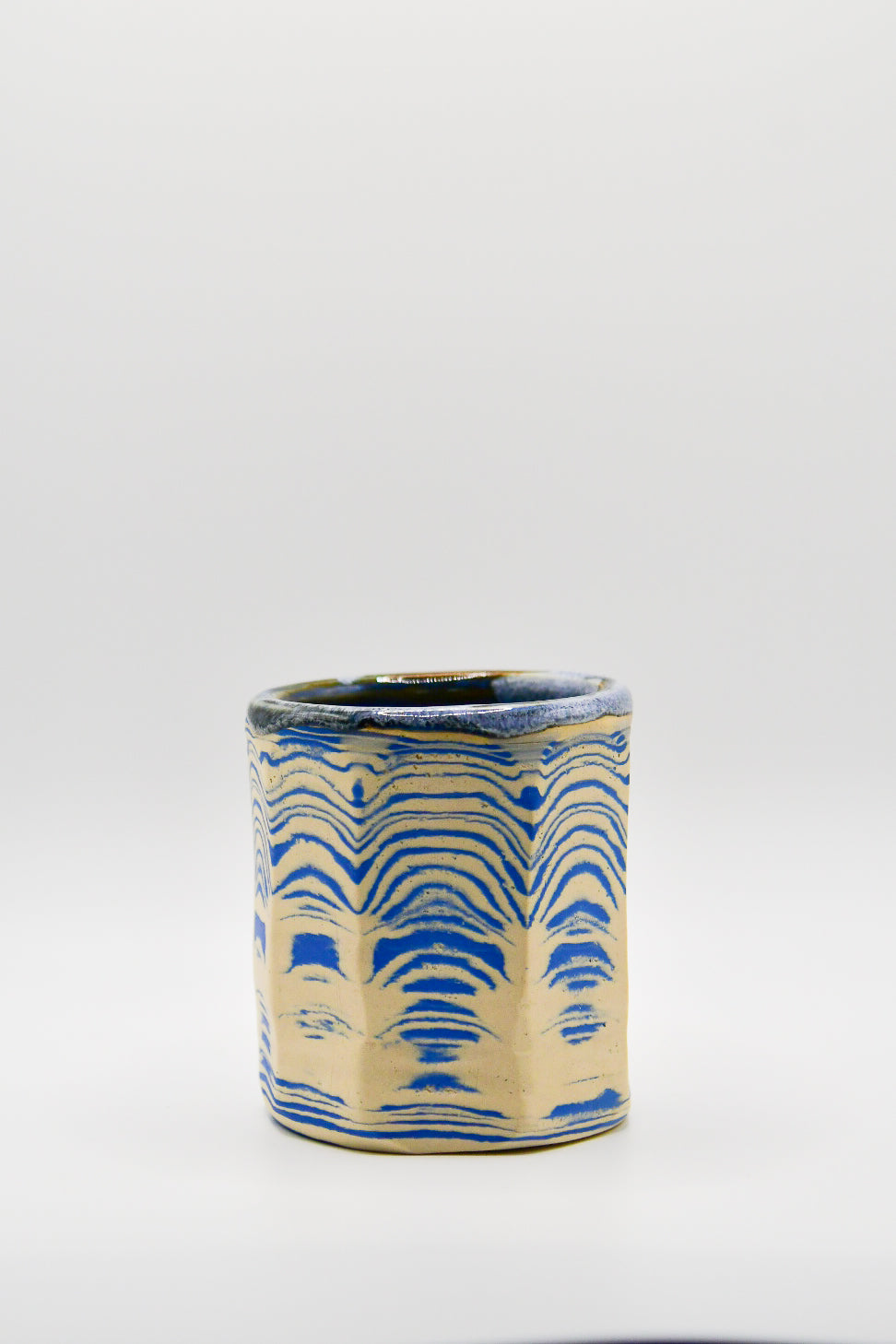 Ceramic cup with blue and beige pattern on a white background