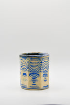 Ceramic cup with blue and beige pattern on a white background